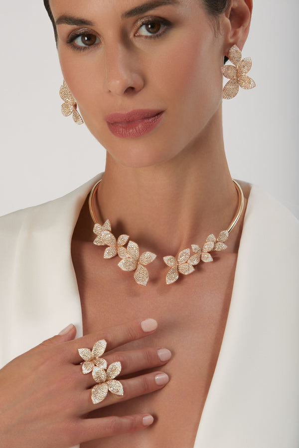 Leaf-shaped earrings, chocker, and Double Flower Ring in 18k Rose Gold with White and Champagne Diamonds on model in white jacket.