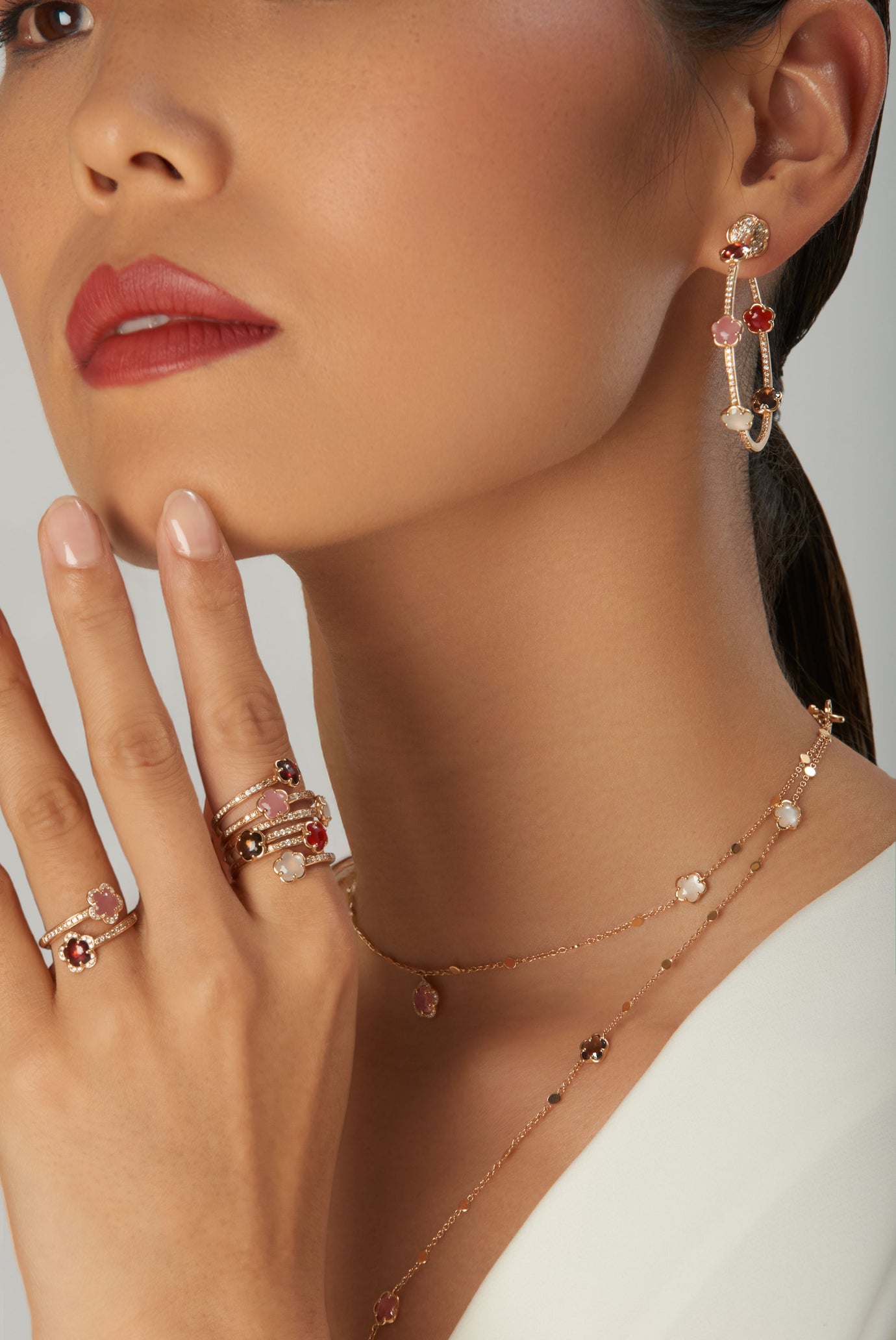 Earrings, rings and necklace in 18k rose gold with gemstones and diamonds, model in white blouse