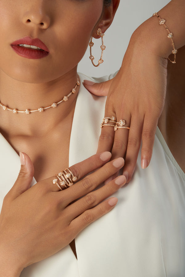Earrings, choker, rings, and bracelet in 18k rose gold with diamonds on woman in white dress