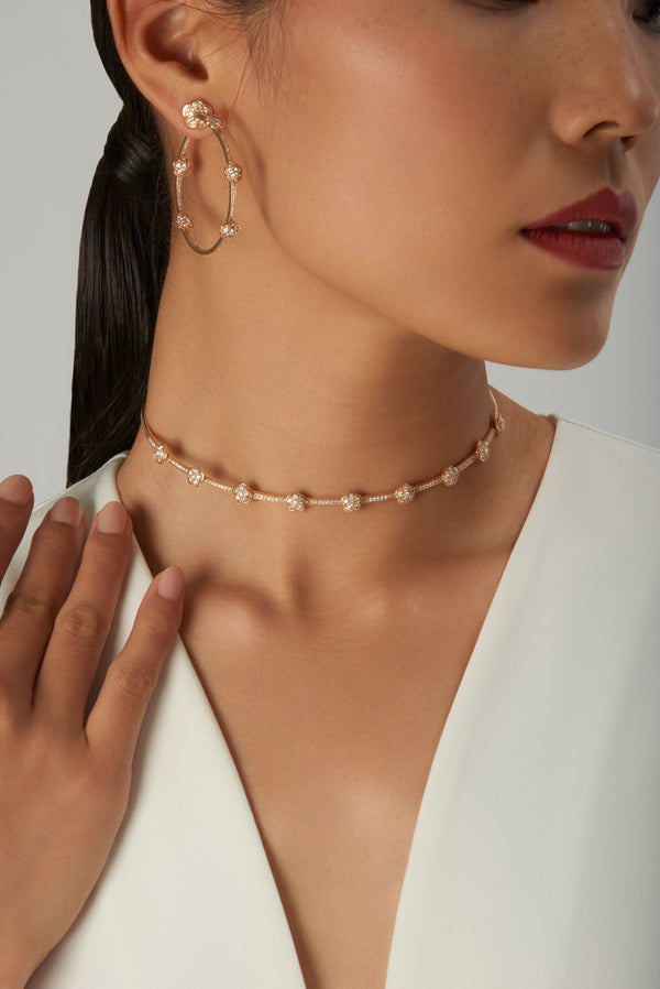 Earrings and choker in 18k rose gold with diamonds worn by model in a white silk top