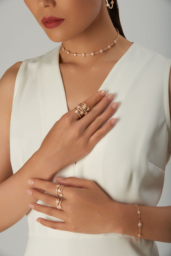 Earrings, choker, rings, and bracelet in 18k rose gold with diamonds on woman in white dress