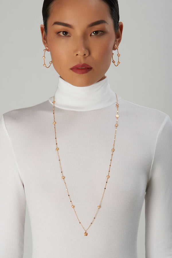 Long necklace and hoop earrings in 18k rose gold with diamonds on model wearing a turtleneck