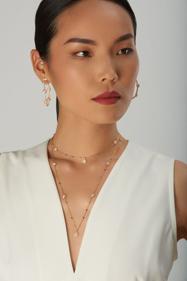 Pendant necklace and earrings in 18k rose gold with diamonds, model in sleeveless white dress