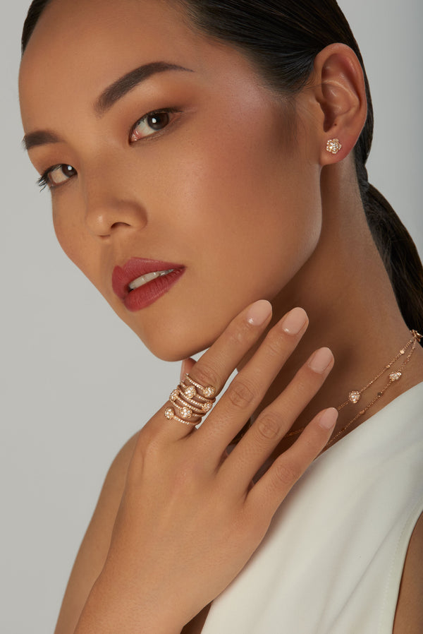 Earrings, ring and chocker in 18k rose gold with diamonds on model wearing a white dress