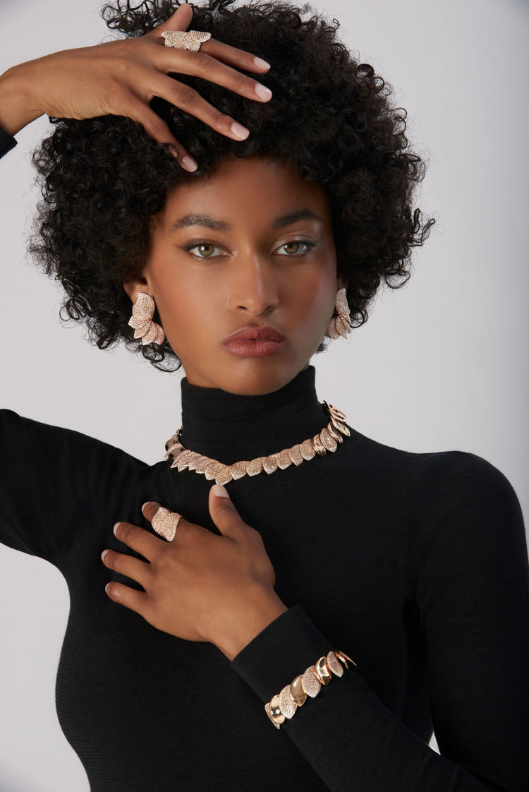 Bracelet, earrings, rings and necklace in 18k Rose Gold with White and Champagne Diamonds on model wearing black turtleneck