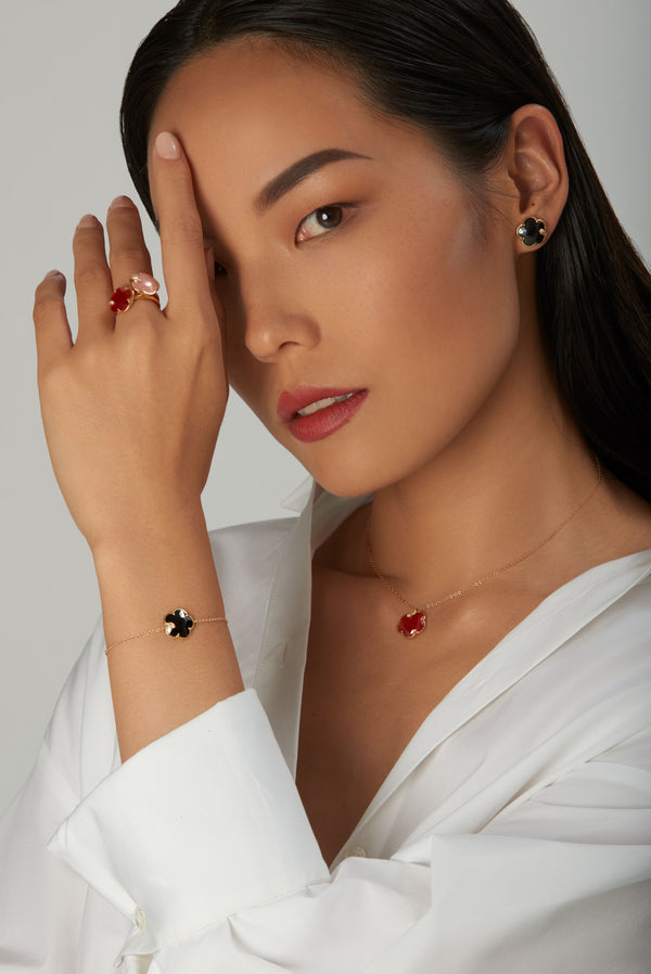 Necklace, earrings, bracelet, and rings with gemstones in 18k gold on model in white shirt