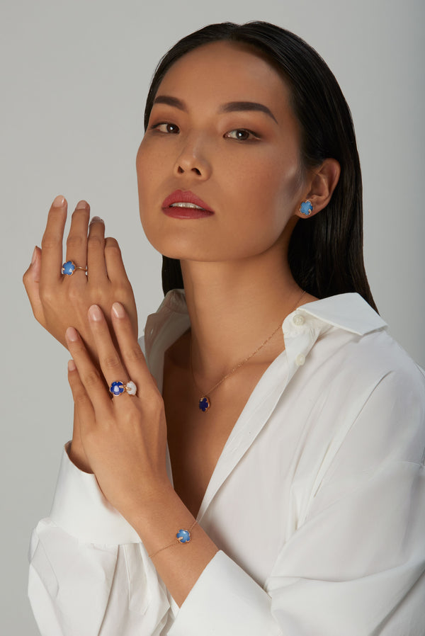 Earring, necklace, rings, and bracelet withcolored gemstones worn by a model in a white shirt