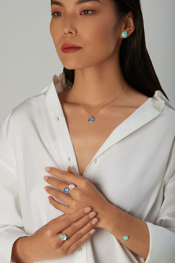 Necklace, earrings, rings and bracelet with blue gemstones, turquoise, and diamonds on model in white blouse
