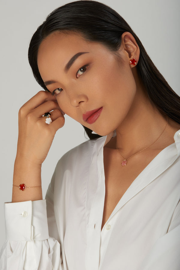 18K rose gold earrings and bracelet with red stones, rings and necklace with colored stones, worn by a model with a white blouse