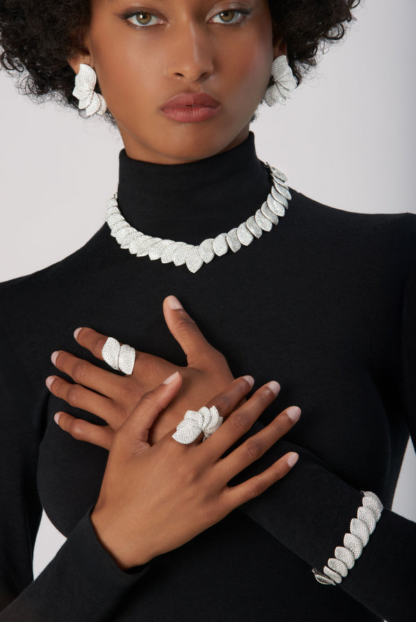 Bracelet, rings, earrings and necklace in 18k White Gold with Diamonds on model wearing black turtleneck.