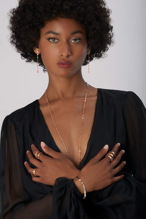 Chain, earrings, rings and bracelet in 18k Rose Gold on model wearing black dress