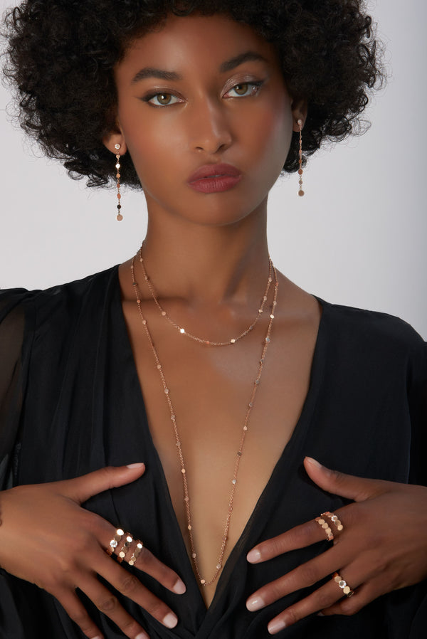 Chain, rings and earrings in 18k Rose Gold on model wearing black dress