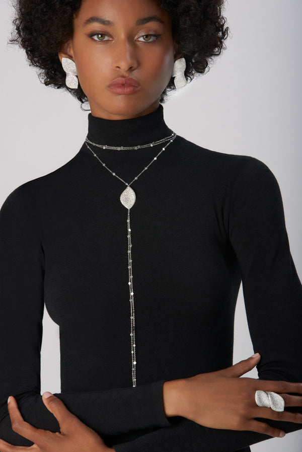 Lariat necklace, ring and earrings in 18k white gold with white diamonds, worn with black turtleneck sweater