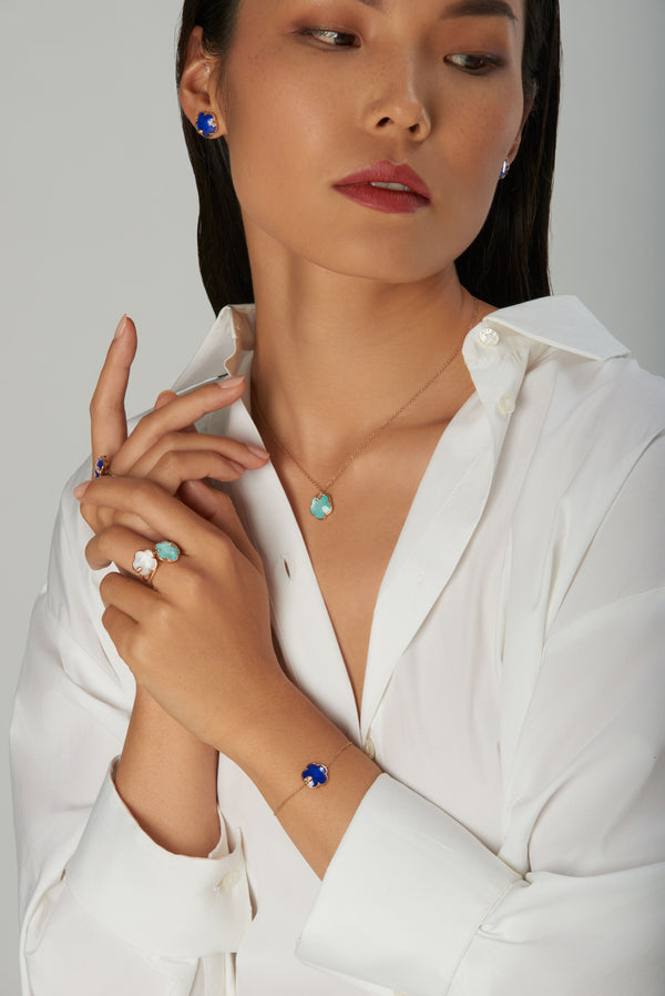 Necklace, earrings, rings in 18k rose gold with coloured gemstones and diamonds on model in white shirt
