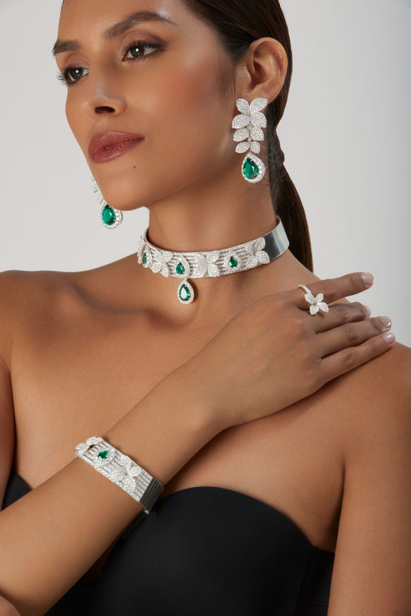 Necklace, earrings, bracelet, ring in 18k white gold with emeralds and diamonds on model in black gown