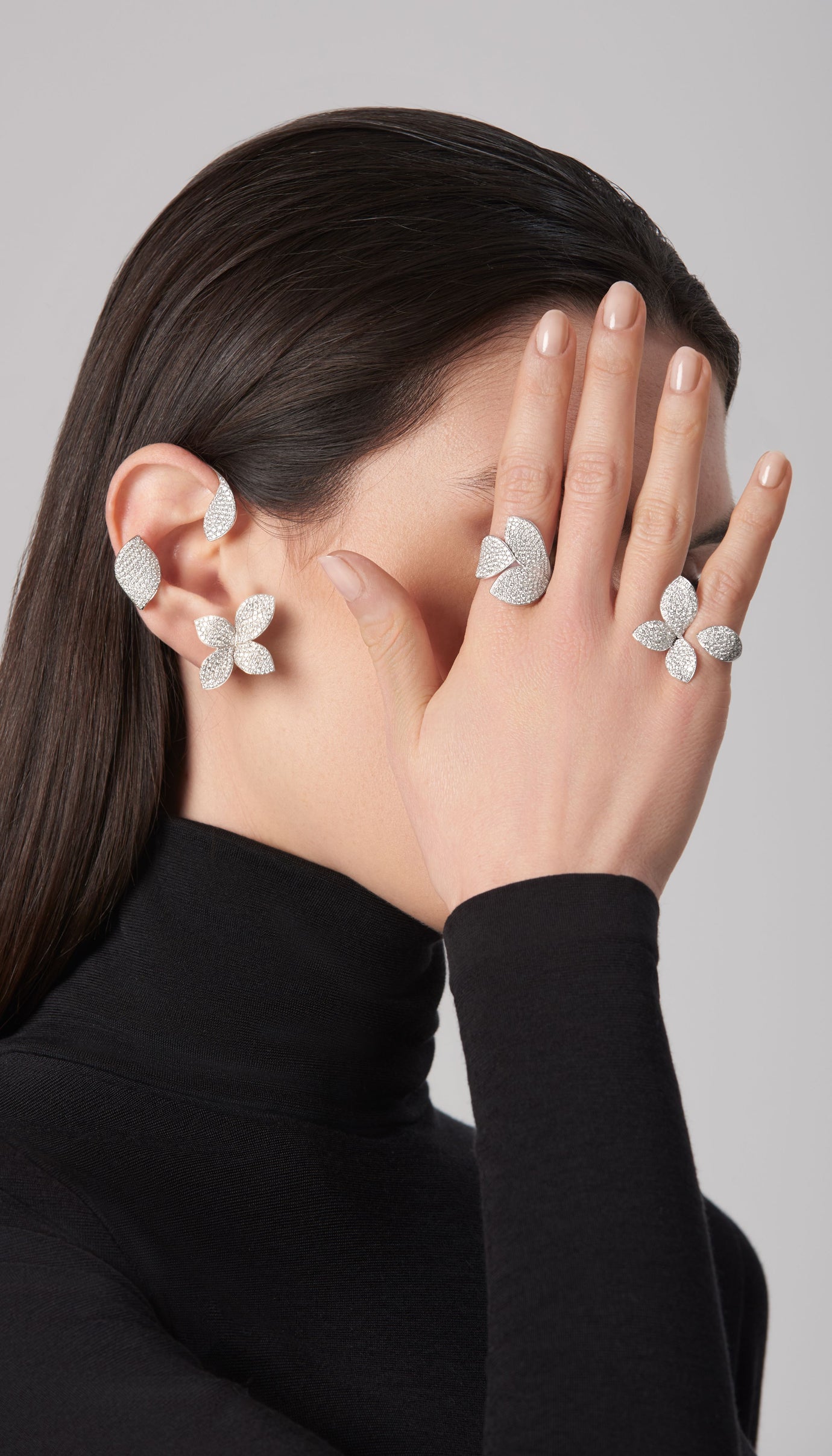 Ear cuff, stud earring and rings in white gold with diamonds on model in black turtleneck