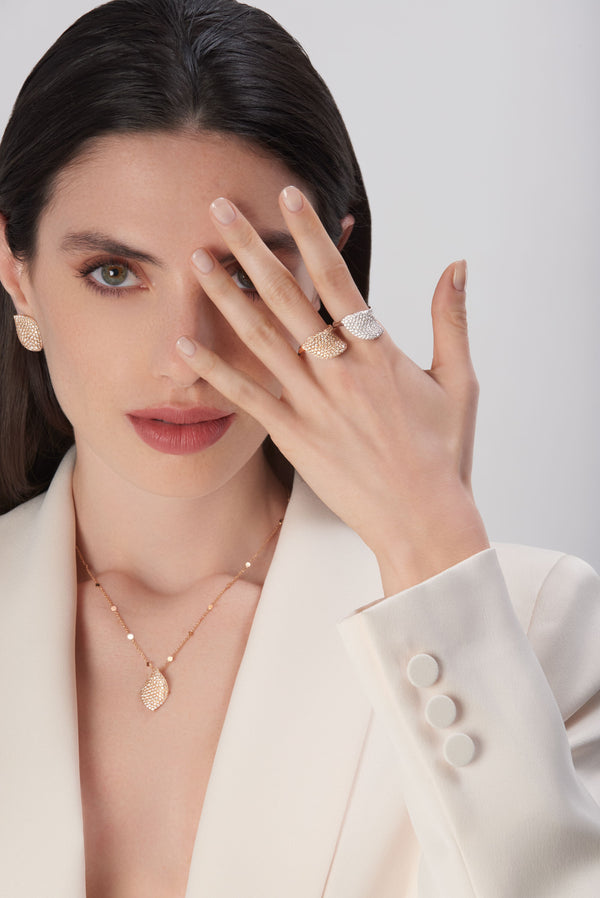 Model with two rings, rose gold and white gold, wearing a rose gold necklace and earrings with white and champagne diamonds.