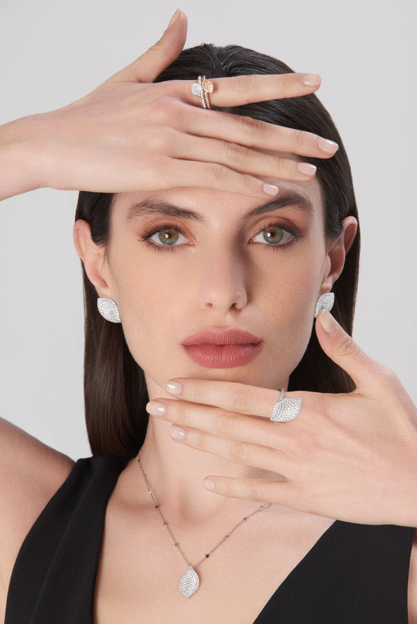 Necklace, earrings and rings in white gold with diamonds, and a ring 18k rose gold with white and champagne diamonds on model wearing black dress