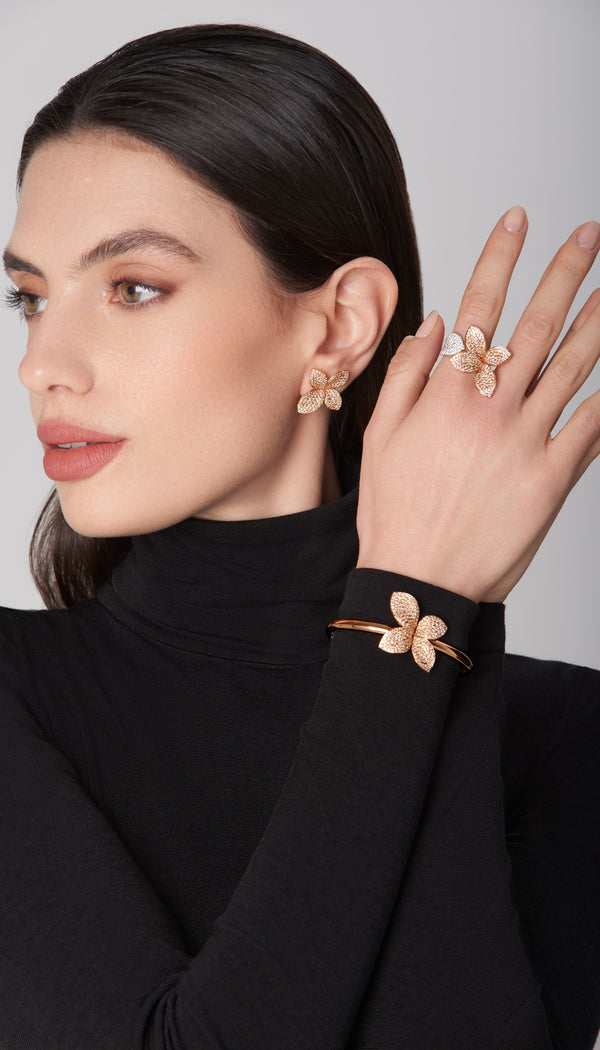 Earrings, ring, and bracelet with diamonds in 18k rose gold worn by model in black turtleneck