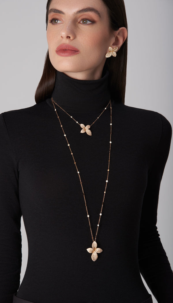 Jewelry set: necklace, rings, earrings in 18k rose gold with diamonds worn by model in turtleneck sweater 