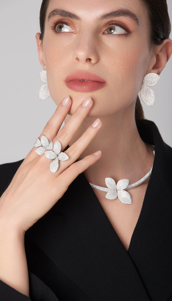 Dangle earrings, necklace, and ring in 18k white gold with diamonds worn by a model with a black jacket