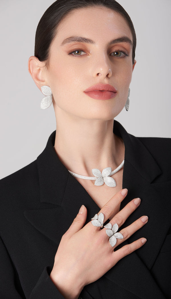 Dangle earrings, necklace, and ring in 18k white gold with diamonds worn by a model with a black jacket