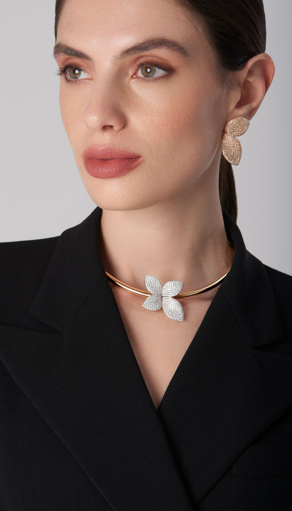 Choker in 18k rose and white gold with diamonds, paired with matching earrings in 18k rose gold, worn by model in a blazer