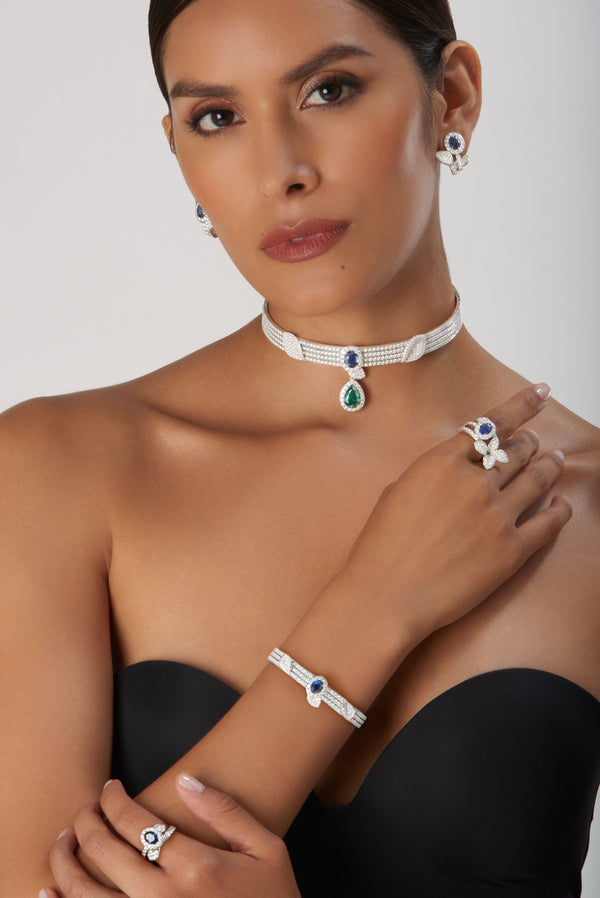 Choker, earrings, bracelet, and rings in 18k white gold with blue sapphires and diamonds, worn by model in strapless dress