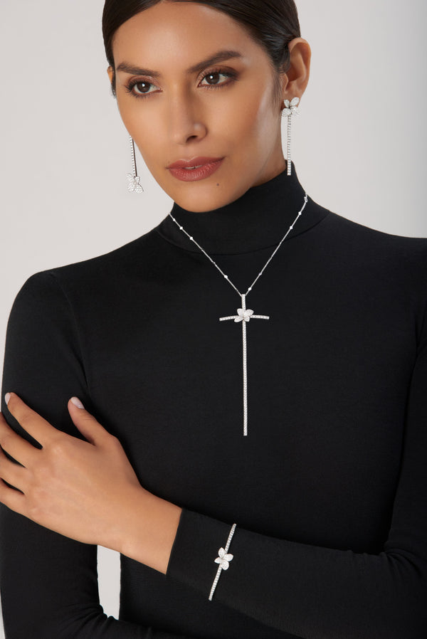 Earrings, necklace and bracelet in white gold with diamonds on model wearing black turtleneck