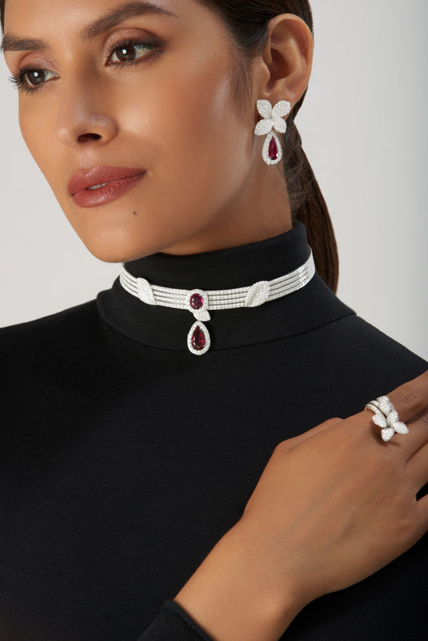 Necklace and earrings in 18k white gold with diamonds and rubies on model wearing turtleneck sweater