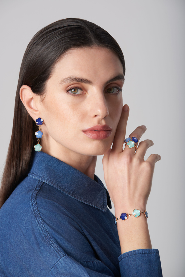 Earrings, ring, and bracelet in 18k rose gold with blue gemstones and diamonds on a model in a denim shirt