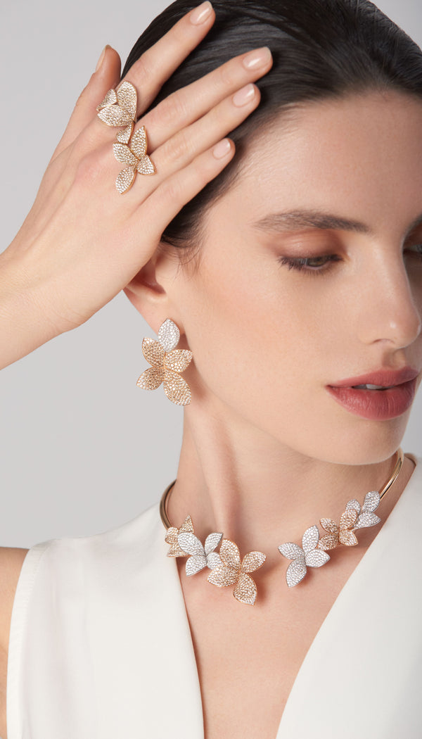 Earrings, necklace, and ring in 18k white and rose with diamonds on model wearing white dress