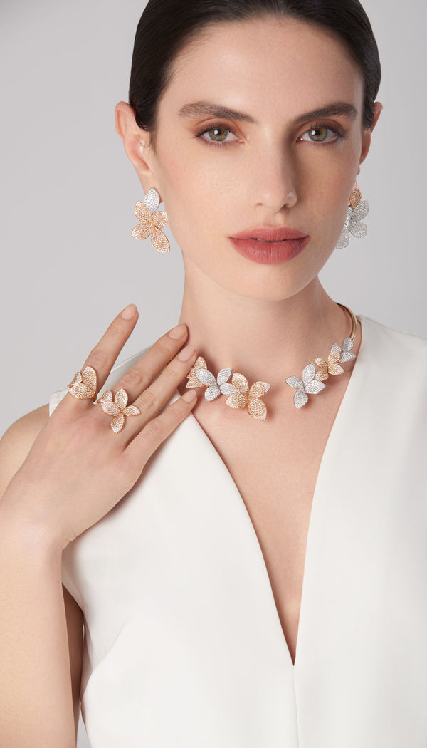 Necklace, earrings, rings in 18k white and rose gold with white and champagne diamonds on model wearing a sleeveless white dress