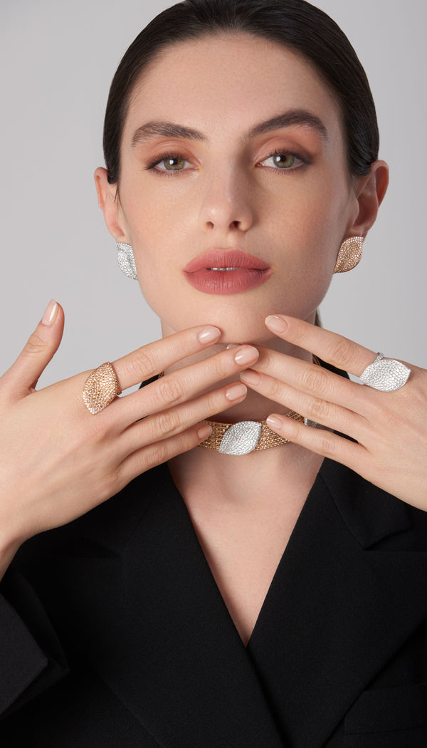 Earrings, necklace, and rings in 18k white and tose gold with whiteand champagne diamonds on model in black blazer