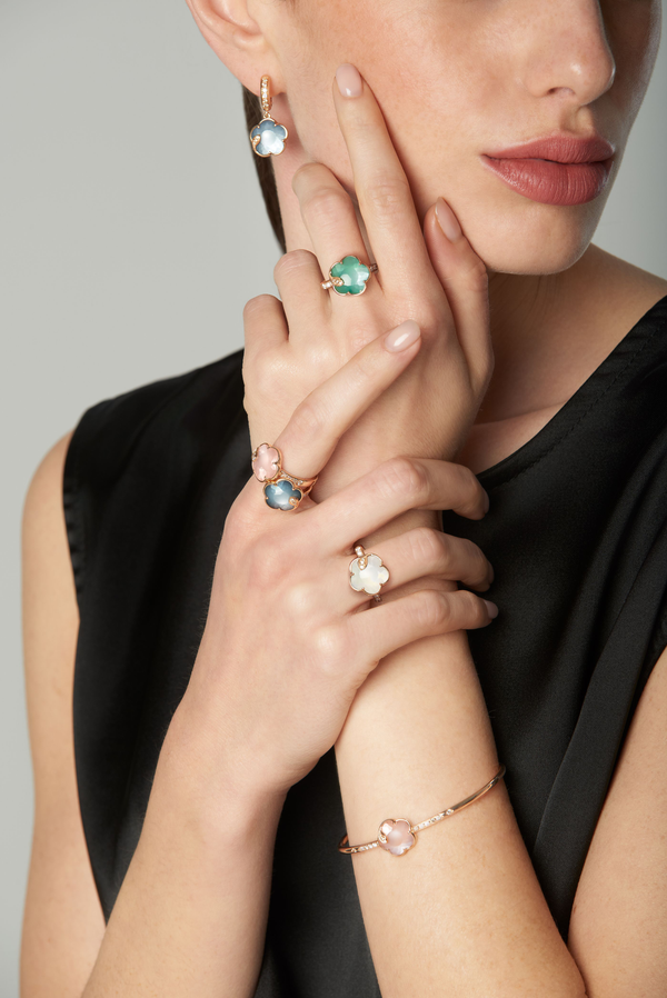 Earring, rings, and bracelet with coloured gemstones and diamonds in 18k rose gold worn by model in black dress