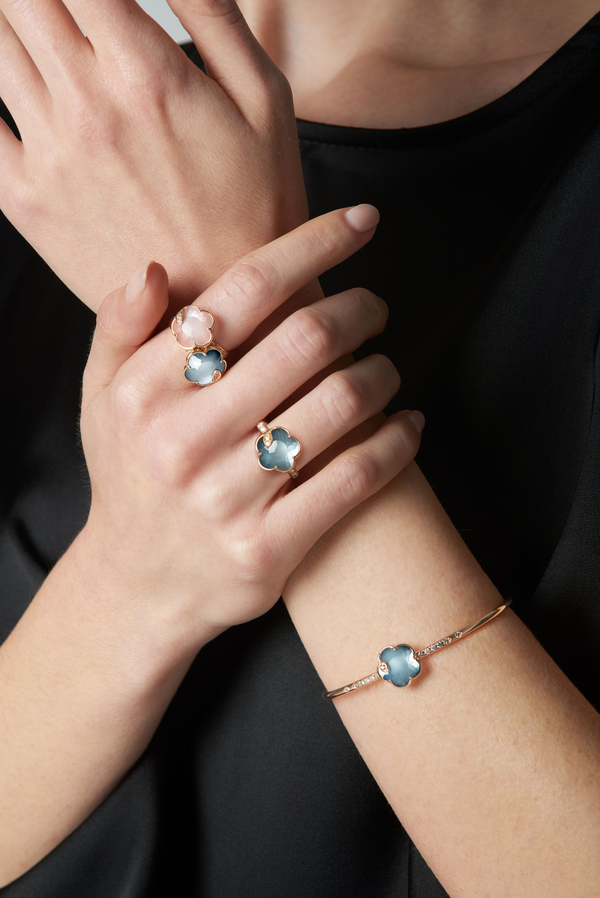 Bracelet and rings in 18k rose gold with blue gemstones and diamonds worn on model in black dress