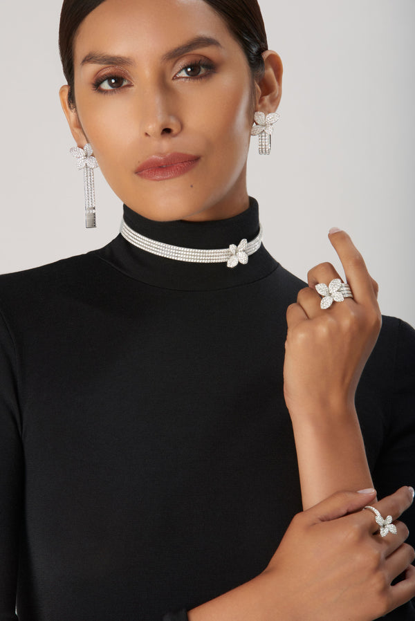 Earrings, choker, rings, and bracelet in 18k white gold with diamonds on model in turtleneck