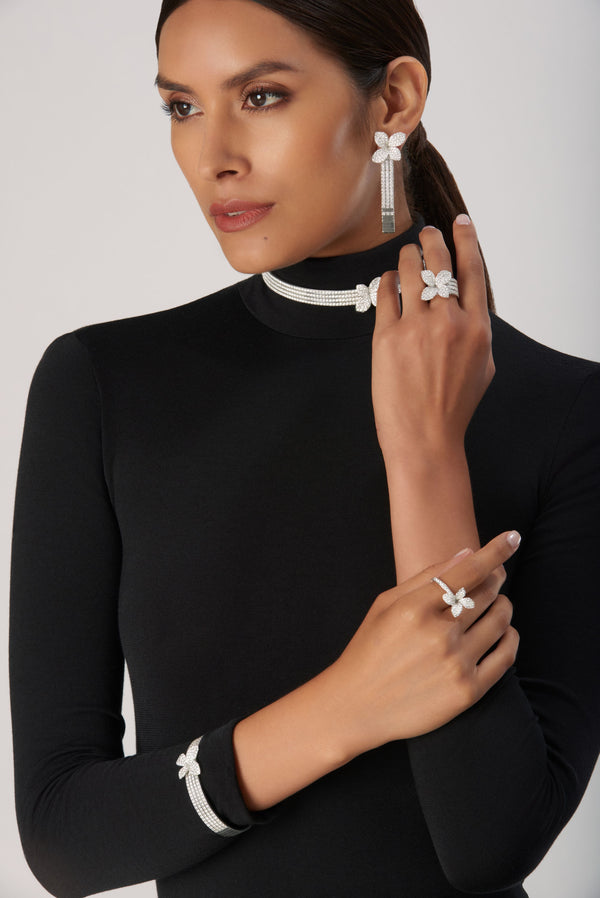 Earrings, choker, rings, and bracelet in 18k white gold with diamonds on model in turtleneck