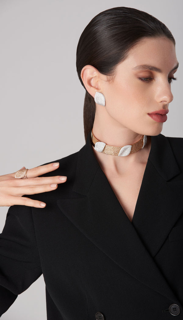 Earrings, choker, and ring in 18k rose and white gold with white and champagne diamonds on a model wearing a black jacket