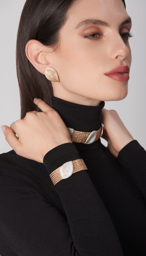 Earrings, necklace, and bracelet in 18k rose gold with white and champagne diamonds on model in black turtleneck