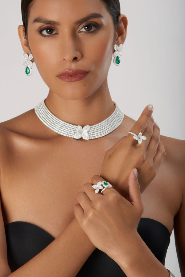 Earrings with emeralds and diamonds, necklace and rings in 18k white gold worn by model in strapless black dress