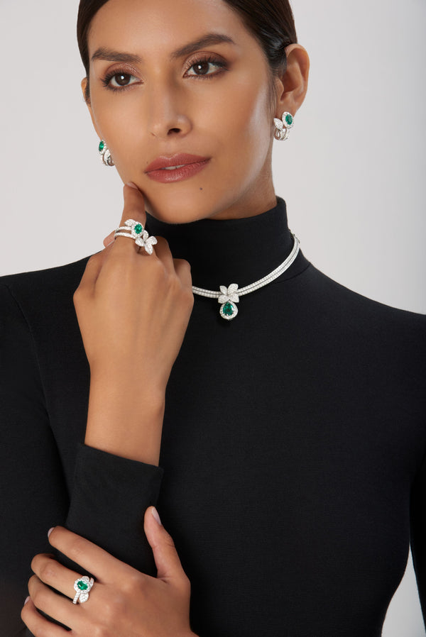 Necklace, earrings, and ring in 18k white gold with diamonds and emeralds on model in black turtleneck