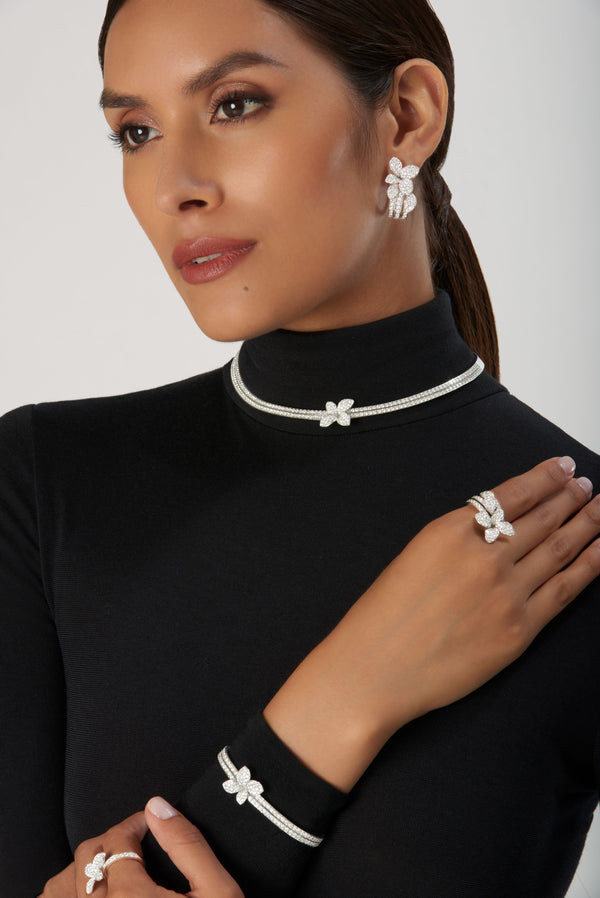 Earrings, choker, bracelet, and ring in 18k white gold with diamonds worn by model in black turtleneck