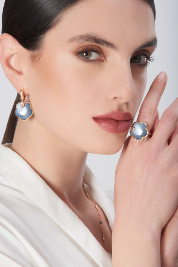 Earrings in 18k rose gold with pearl gem and diamonds and ring in 18k rose gold with blue gemstones on model in white dress