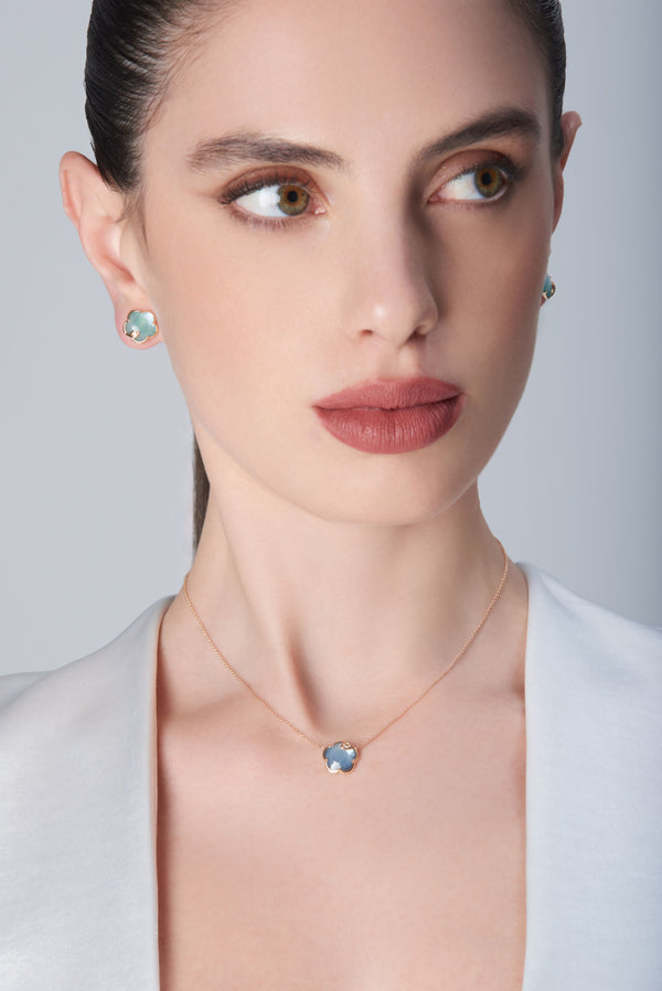 Earrings and necklace in 18k rose gold with coloured gemstones and diamonds on model in white blouse