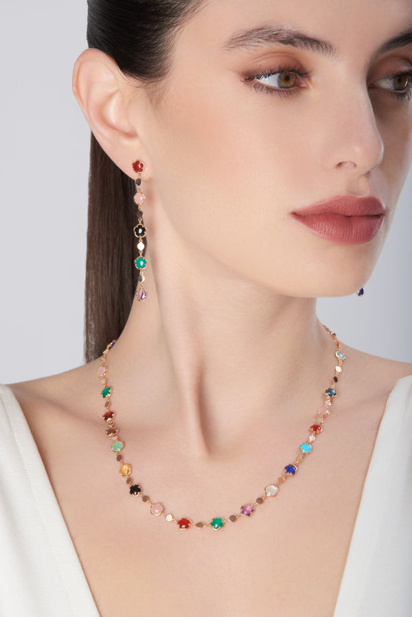 Necklace and earrings in 18k rose gold with colorful gemstones on model in white blouse