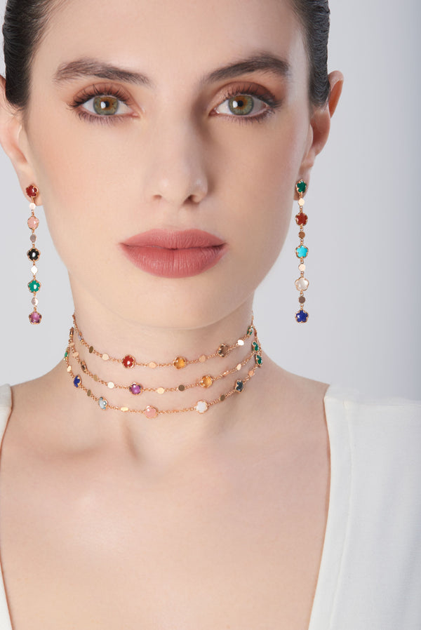 Necklace and earrings in 18k rose gold with multicolored gemstones on model in a white dress