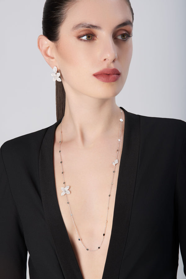 Pendant necklace in 18k white gold with diamonds and matching earrings on model dressed in black