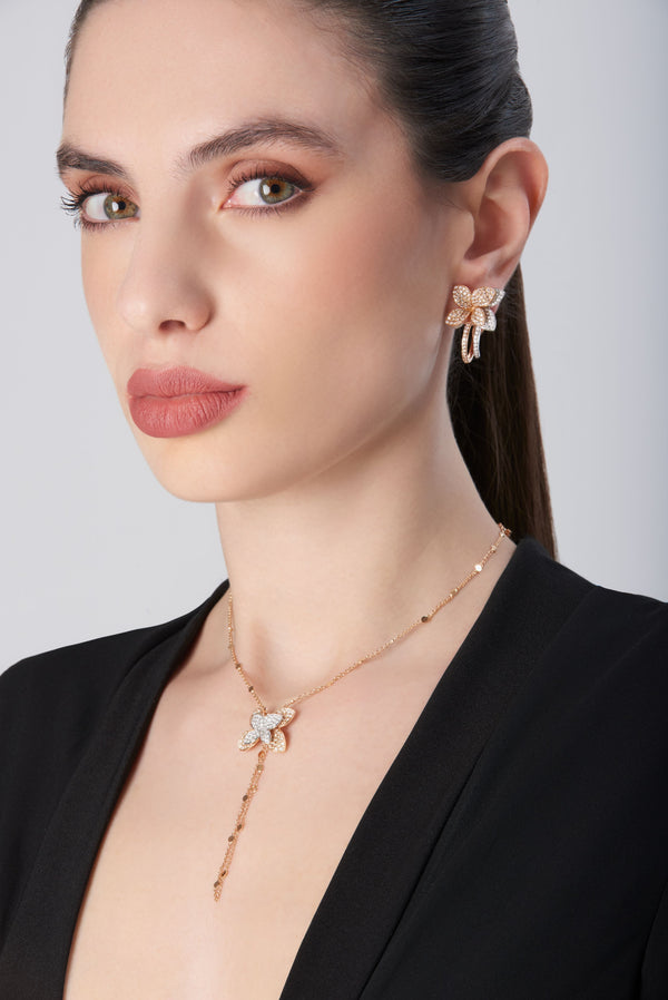 Necklace and earrings in 18k white and rose gold with diamonds on model wearing black dress