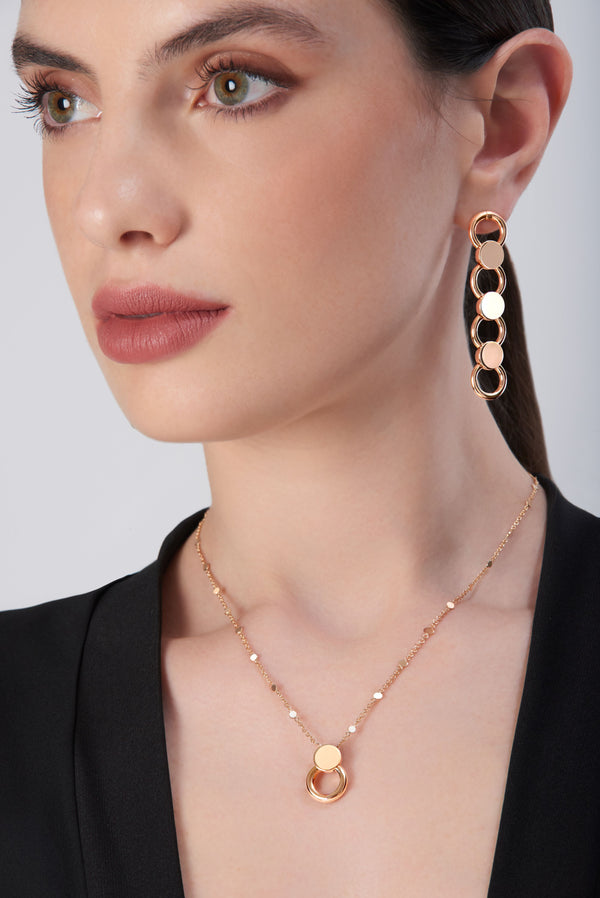 Earring and necklace in 18k rose gold featuring circle motifs on model in black jacket